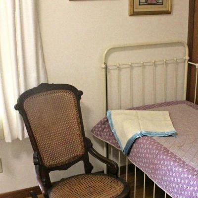  Framed stained glass artwork, antique rocking chair with cane seat and back, antique iron child's bed (recommended for display,...