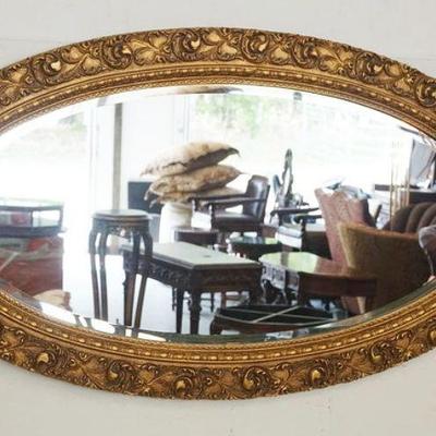 1022	OVAL BEVELED EDGE MIRROR IN ORNATE GILT FINISH FRAME, APPROXIMATELY 24 1/2 IN X 44 IN
