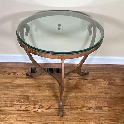 ROUND GLASS SIDE TABLE | With a round glass top on a shaped bronze tone metal frame; h. 25-1/2 x dia. 29 in. [appearing in overall very...