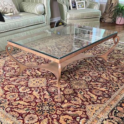 GLASS COFFEE TABLE | Low table with a glass top and a brass toned metal frame with shaped x-stretcher; h. 19 x 50 x 34 in.