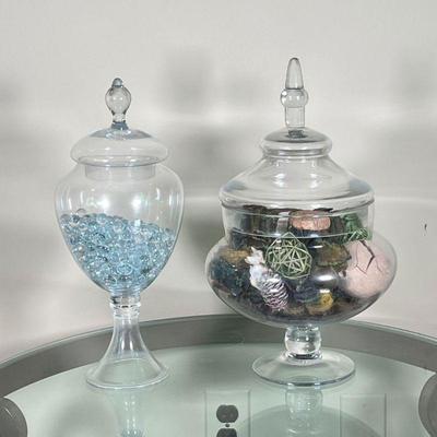 (2pc) LIDDED GLASS JARS | Covered glass jars, one with Elements label and one with Manerisms label; h. 15 x dia. 10 in. (tallest)