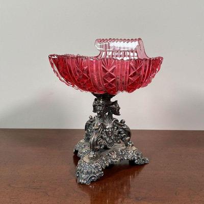 CRANBERRY GLASS VIDE POCHE ON STAND | Shell-form cut cranberry glass on a silver tripod base with figural motif - h. 7 in.