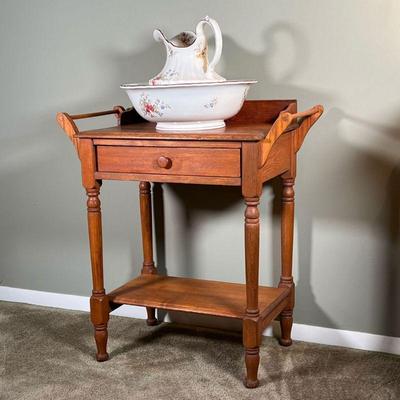 (3pc) WASHSTAND SET | Comprising an antique Cauldon stoneware wash bowl and water pitcher resting atop an early turned wood washstand...