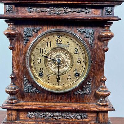 ANSONIA SHELF CLOCK | Carved oak wood case with three finials and brass appliquÃ©, the face with Arabic numerals, the movement marked...