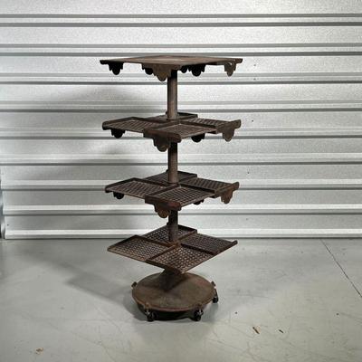INDUSTRIAL IRON RACK  | Having three open work shelves and a top solid shelf rotating around a central shaft on a lower base rolling on...
