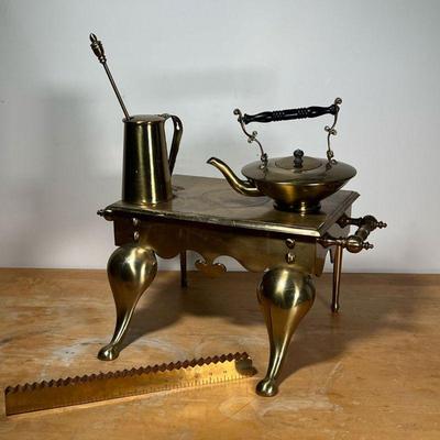 (4pc) MISC. BRASS  |
Including a tall pitcher with stirrer, a teapot, and a large trivet - l. 22 x w. 16 x h. 11-1/2 in. (trivet)