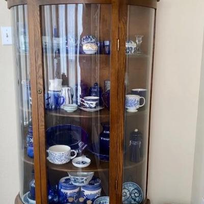 Curved glass curio cabinet with cobalt blue glass inside