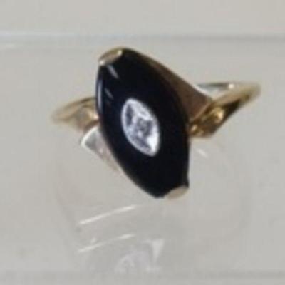 1044	10K YELLOW GOLD RING W/ BUFF TOP OVAL CUT GENUINE BLACK ONYX W/ WHITE GOLD TRIM CONTAINING ONE DIAMOND WEIGHING APP. 0.005 CARATS....