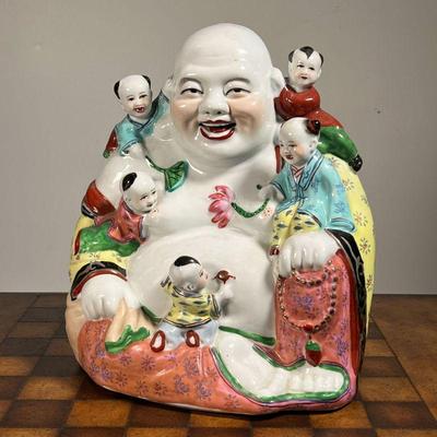 HAPPY BUDDHA PORCELAIN FIGURE  |  Chinese porcelain figure of a smiling Buddha, with five children climbing on him - l. 11 x w. 6 x h. 13...