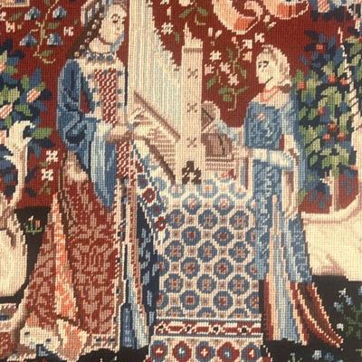 NEEDLEPOINT EMBROIDERED SCENE  |  Showing two figures with a unicorn and lion among smaller animals, with 1983 dedication on verso - w....