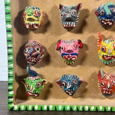 MEXICAN MASK CERAMIC  |  Ceramic wall hanging displaying miniature colorful masks, signed "Ortega" on the side - w. 8 3/4 x h....