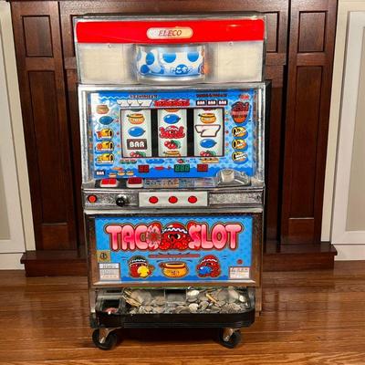 ELECO TACO SLOT MACHINE  |
No. 084949, with a collection of game tokens, many Japanese, key present - w. 18-1/2 x h. 37 in. [n.b. dolly...