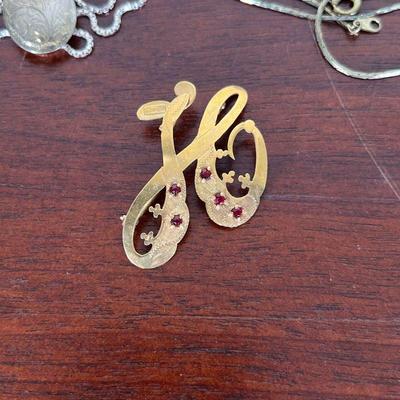 GOLD & STERLING JEWELRY  |  
Including a sterling silver chain with a silver-tone pendant, an 18kt gold pin with 5 red gemstones (3.0g),...