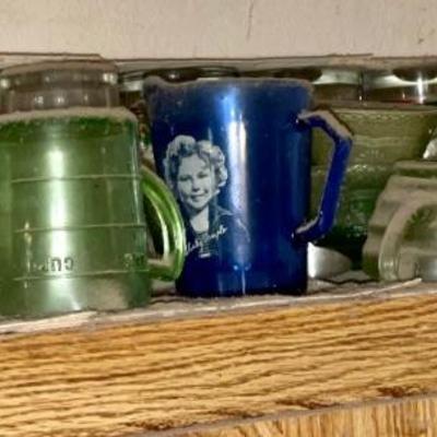 Shirley Temple blue creamer next to a green Vaseline glass measuring cup 
