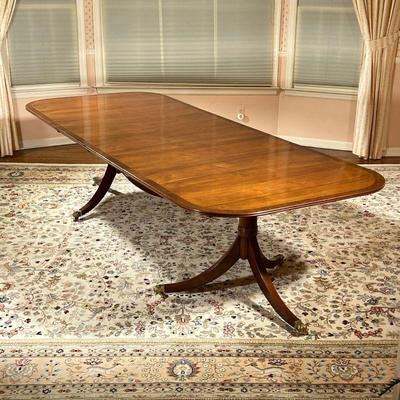 DOUBLE PEDESTAL DINING TABLE | Mahogany and burlwood veneer top, two pedestal sections raised on tripod bases with brass paw feet on...