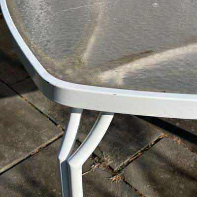 PATIO DINING TABLE | Outdoor dining table having a white tube frame with frosted glass top over four legs, of square shape with rounded...