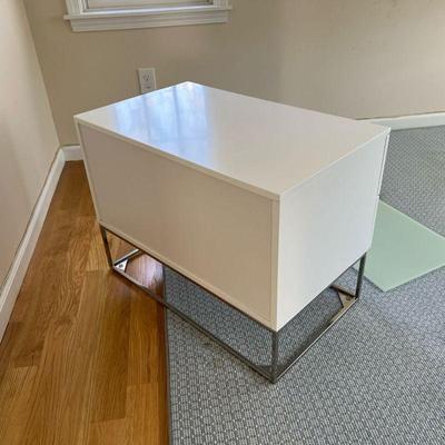 SMALL WHITE CREDENZA | Modern style side table of small size, having two drawers with chrome hardware and a lower shelf with glass floor...