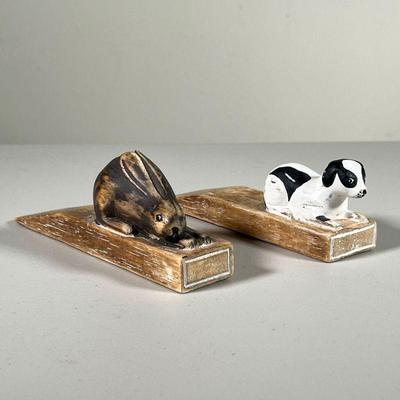 (2PC) CARVED ANIMAL DOORSTOPS | Painted & Carved wooden doorstops in the form of a bunny and a dog. - l. 7 x w. 1.5 x h. 2.5 in 