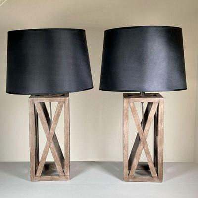 (2PC) CONTEMPORARY WOOD LAMPS | Pair of contemporary wood table lamps with black shades over x-form wood bases. w. 6.5 x h. 25.5 x dia....
