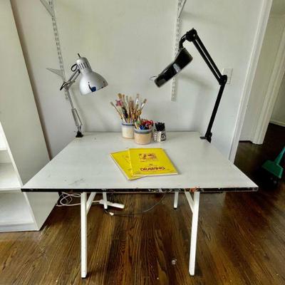 Lot 025-BR2: Art Table Vignette

Features: 
â€¢	Art table with tilting top and table lamps
â€¢	All photographed artist supplies included...