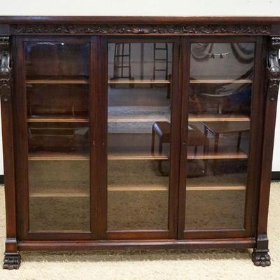 1118	MAHOGANY TRIPLE DOOR BOOKCASE W/CARVED WINGED GRIFFINS & PAW FEET, ONE DOOR GLASS REPLACED W/PLEXI, APPROXIMATELY 69 IN X 17 IN X 63...