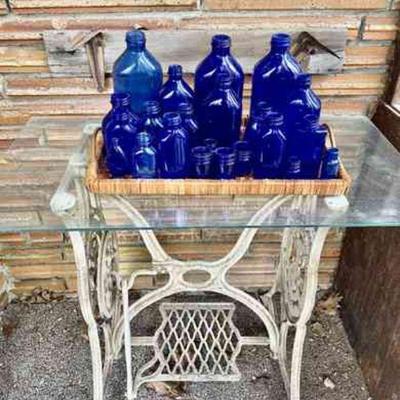 Lot 028-P: Cobalt Blue Glass Vignette

Features:
â€¢	Collection of cobalt blue glass bottles and jars, over 1 dozen
â€¢	Wicker tray
â€¢...