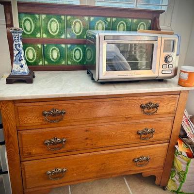 Vintage chest of drawers with marble top and green tile backsplash 