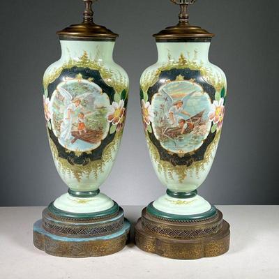 (2PC) PAIR PAINTED CERAMIC LAMPS | Each decorated with hand-painted scenes with an angel and baby, on shaped and reticulated brass bases.