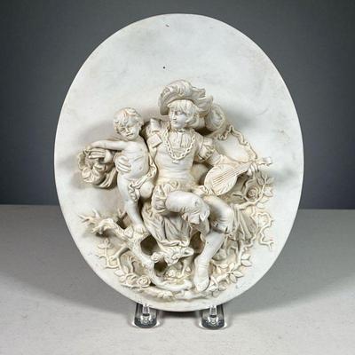CERAMIC RELIEF PLAQUE | Showing a bard with lite holding a cupid before a rose bush, with blue crown mark on verso.