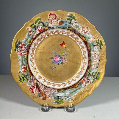 CAPODIMONTE PORCELAIN PLATE | Gilt plate with raised border depicting various nature scenes featuring cupids, chariots, and more.