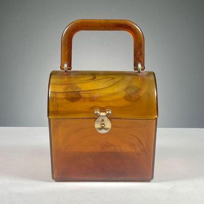 AMBER LUCITE MIDCENTURY HANDBAG | Bakelite type handbag with hinged lid and bail handle. Dimensions: w. 5.75 x h. 6 in
