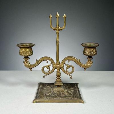 BRASS NEPTUNE CANDLEHOLDER | Brass candelabra featuring trident in the middle with fish and sea serpent relief on base.