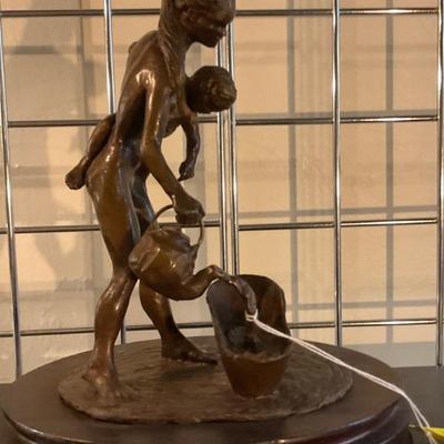 Mother preparing to bathe child bronze.