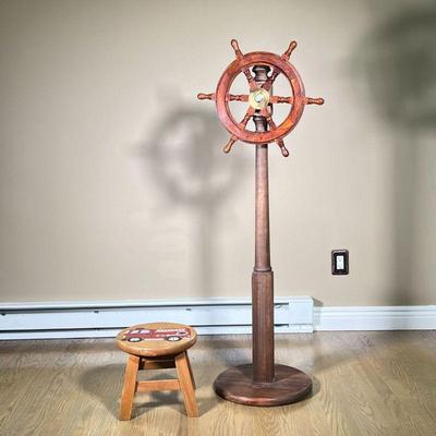 (2PC) MISC. DECOR | Including a small free spinning ship wheel on wooden stand and small children’s stool featuring a painted carving of...