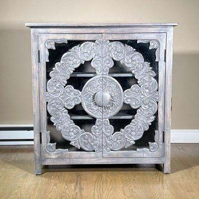 CARVED WOOD & GLASS CABINET | Carved gray washed wood and glass doors open to interior shelving. - l. 16.25 x w. 37.25 x h. 38.5 in
