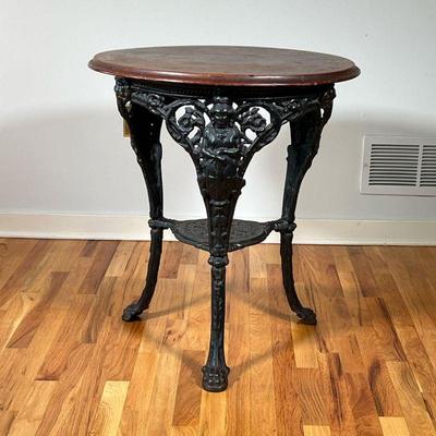 CAST IRON PUB TABLE | Distressed wood top on a wrought iron tripod base with figural knees and claw feet. - h. 29.5 x dia. 26 in