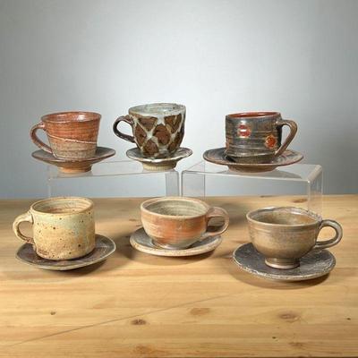 (6PC) MEG SMEAL POTTERY CUPS & SAUCERS | Mostly with brown glaze by Meg Smeal and other Potters. - dia. 6.5 in (largest saucer)
