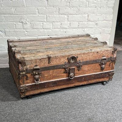 ANTIQUE WOOD TRUNK | An antique wood trunk with iron hardware and four casters. - l. 34 x w. 20 x h. 14.5 in
