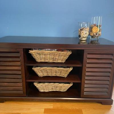 This classic style console features two doors for storage and a 3-shelf display.  Baskets included.