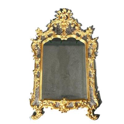 GILT FRAMED MIRROR | Intricately carved gilt frame with sectioned mirrored border, floral and wreath carvings around. - w. 32.5 x h. 54 in 