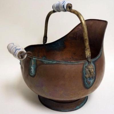 1122	COPPER SKUTTLE BUCKET	COPPER SKUTTLE BUCKET WITH PORCELAIN HANDLES AND EMBOSSED LION HEADS, APPROXIMATELY 17 IN H
