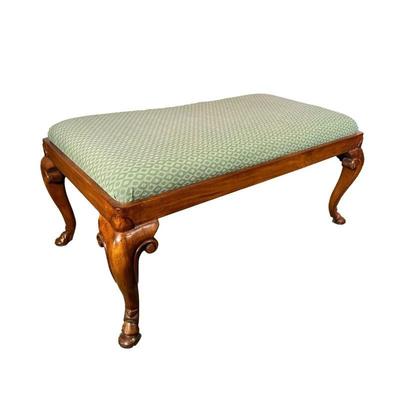 CARVED UPHOLSTERED OTTOMAN | Carved wood ottoman with a green upholstered cushion, cabriole legs with scroll decoration terminating in...