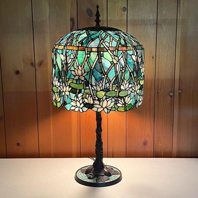 STAINED GLASS LAMP W/LILY PAD FLOWERS | Lamp has ornate base with leaves and vines. Shade has green as the primary color. Double lights...