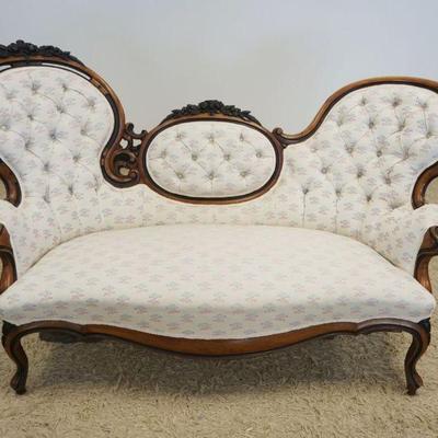 1209	ORNATE WALNUT VICTORIAN SETTEE WITH FLORAL CARVED CREST AND EBONIZED FINISHTRIM AND TUFTED BACK UPHOLSTRY, APPROXIMATELY 64 IN LONG

