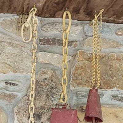 Set of cowbell on heavy yellow chains functioning as chimes
