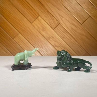 (2PC) PAIR SMALL JADE FIGURINES | Small lion carved spinach jade figurine and smaller elephant figurine on a conforming wooden stand. -...