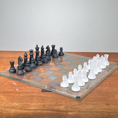 GLASS CHESS SET | Clear glass chessboard featuring sandblasted glass white pieces and black glass pieces. - l. 15 x w. 15 in 