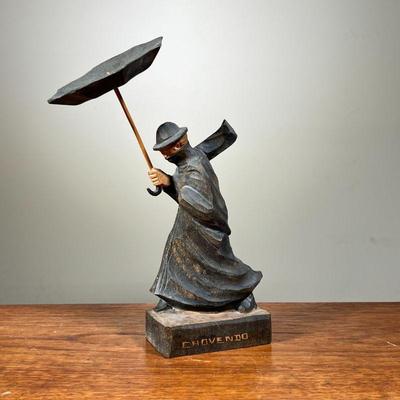 CHOVENDO WOOD SCULPTURE | Shows man in heavy rainstorm with umbrella blown out. Signed â€œChovendoâ€ on bottom. - l. 6 x w. 3.5 x h. 9.5...