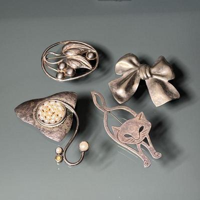 (4PC) STERLING SILVER PINS | Including a bow form pi (missing pin), a cat form pin, a pin mounted with pearls, and a pin with openwork...
