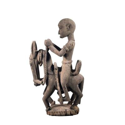 AFRICAN CARVED WOOD FIGURINE | Showing man riding horse with elongated face mounted to black stand. - l. 12.5 x w. 8 x h. 24 in 
